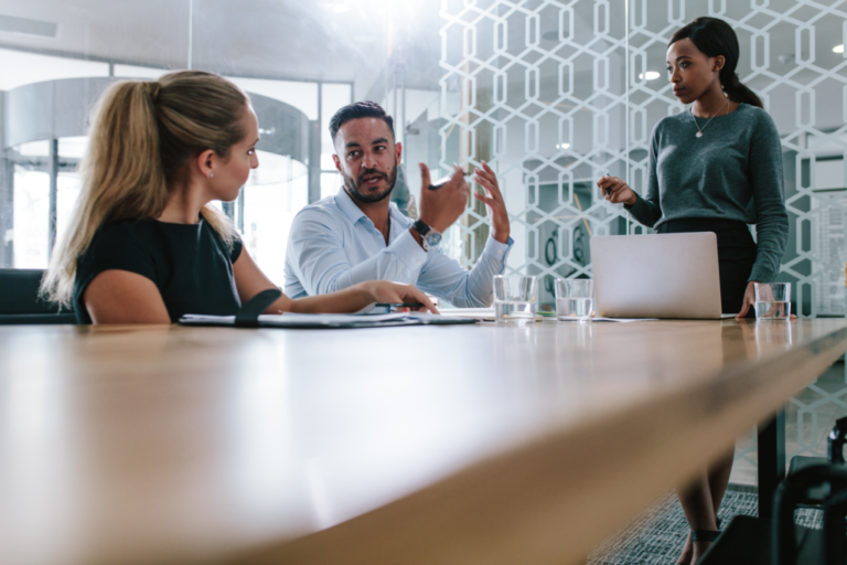 Young man sharing his views with coworkers in boardroom during business meeting - Tech consulting